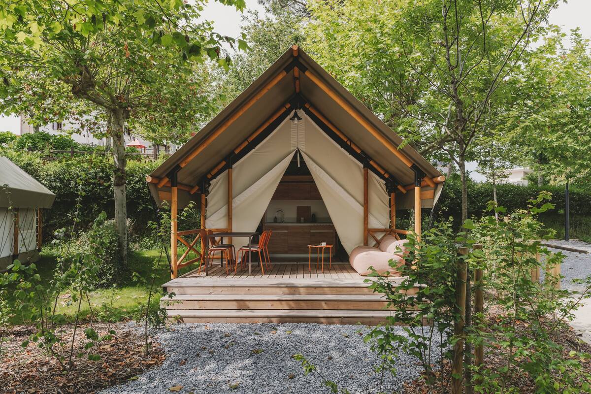 A wooden cabin with a pitched roof, a small porch with chairs, and a table.