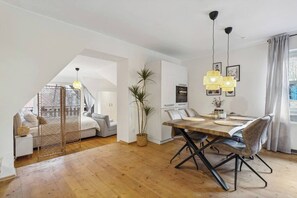 Ein modernes Interieur mit Essbereich, einer Treppe zu einem Schlafzimmer-Loft und einer großen Topfpflanze.