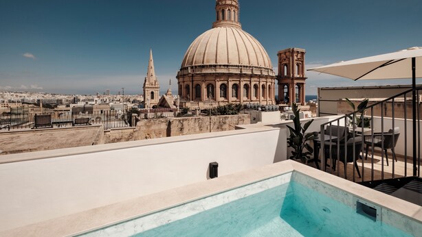 Una piscina en la azotea con vistas despejadas a una cúpula grande y un campanario al fondo.