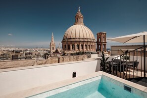 Una piscina en la azotea con vistas despejadas a una cúpula grande y un campanario al fondo.