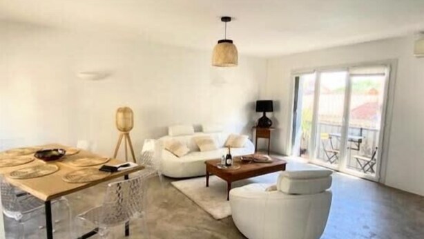 Ein großzügiger Wohnbereich mit einem weißen Sofa, einem Holztisch und einem Esstisch mit Platzsets.