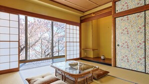 A traditional Japanese room with tatami flooring, a low table with cushions, and a sliding door with floral patterns. - UNDER CURRENT ATAMI | Private Villa with Hot Springs & Fireworks View (熱海市)