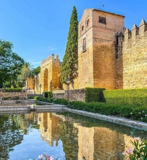 A historic stone building with a moat and a clear reflection in the water.