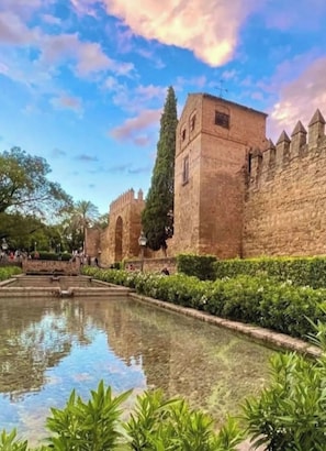 A historic stone building with a courtyard and a reflecting pool.