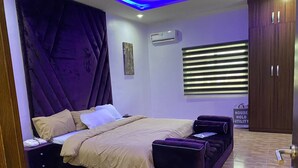 Una camera da letto moderna con un letto, un tavolino, una sedia, un tappeto e un cartello appeso al muro.