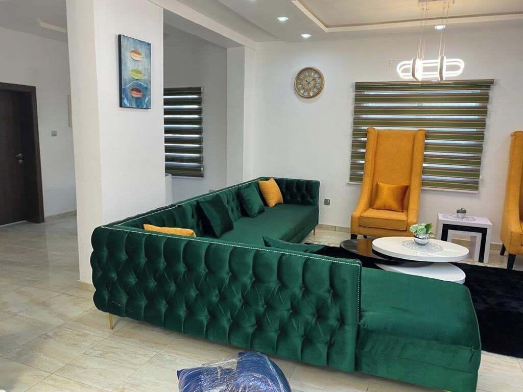 A modern living room with a green sectional sofa, a yellow armchair, and a round coffee table.