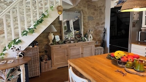 Una cocina rústica con una mesa de madera, un frutero y una lámpara colgante.