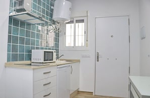 A compact kitchen with a microwave, sink, and white cabinets. - Loft La Flor       . (Conil de la Fra.)