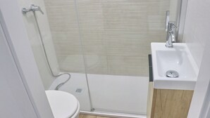 Une salle de bain avec une douche à parois de verre, un lavabo blanc et des toilettes.