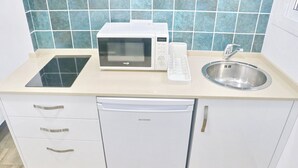 Une cuisine compacte équipée d’un four à micro-ondes, d’un évier et d’un lave-vaisselle.