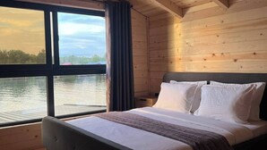 A wooden cabin bedroom with a large window overlooking a body of water. - Bonita cottage in Ada Bojana (Ulcinj Municipality)