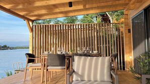 A wooden deck with outdoor seating, a view of the water, and a wooden fence. - Bonita cottage in Ada Bojana (Ulcinj Municipality)