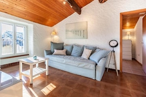 Una sala de estar acogedora con un sofá, una mesita, un reloj y una ventana.