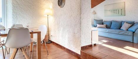 A cozy room with a dining area, a sofa, and a clock on the wall.