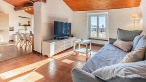 A cozy living room with a TV, sofa, and dining area. - Rustic Apartment First Floor (Castel San Pietro)
