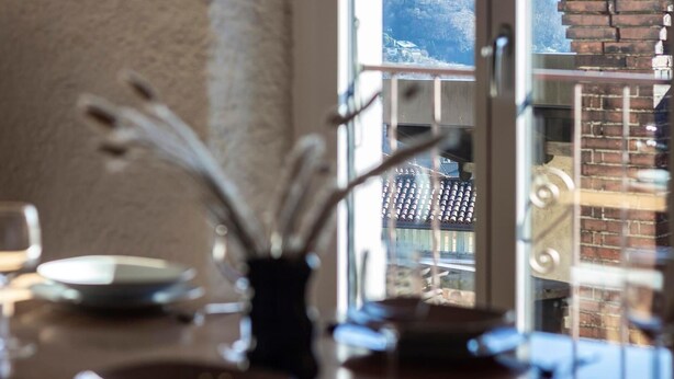 A view through a window with a traditional building and mountains in the background. - Rustic Apartment First Floor (Castel San Pietro)