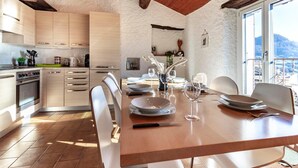A modern kitchen with wooden cabinets and a dining area set for a meal. - Rustic Apartment First Floor (Castel San Pietro)