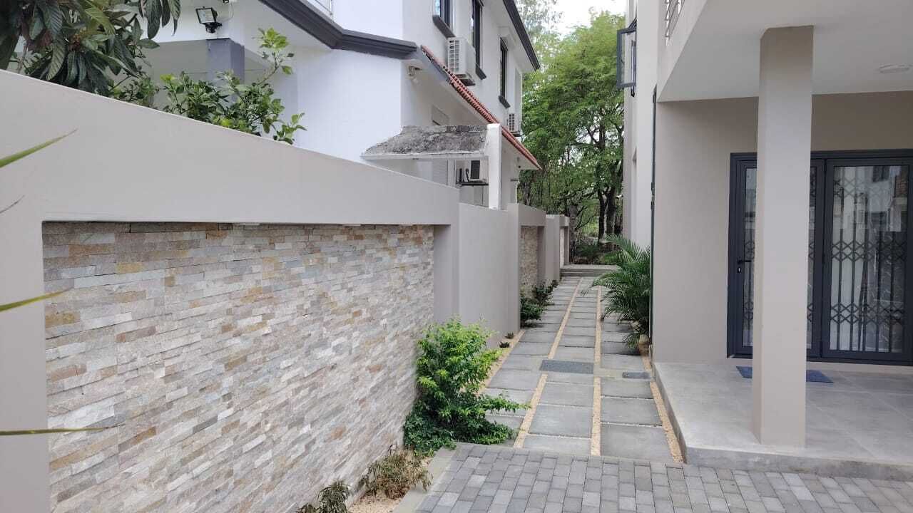 A narrow pathway flanked by a stone wall and a building with a tiled roof.