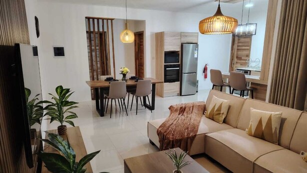 A modern living room with a sofa, coffee table, and dining area.