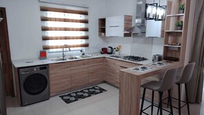 A compact kitchen with a built-in washer, a gas stove, and a small dining area with two chairs.