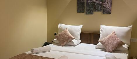 A neatly made bed with a wooden headboard, two pillows, and a decorative wall piece above it.