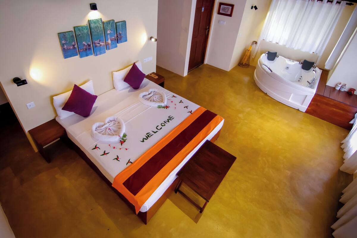 A hotel room with a bed, a bathroom with a bathtub, and artwork on the walls.