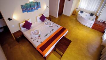 A hotel room with a bed, a bathroom with a bathtub, and artwork on the walls.