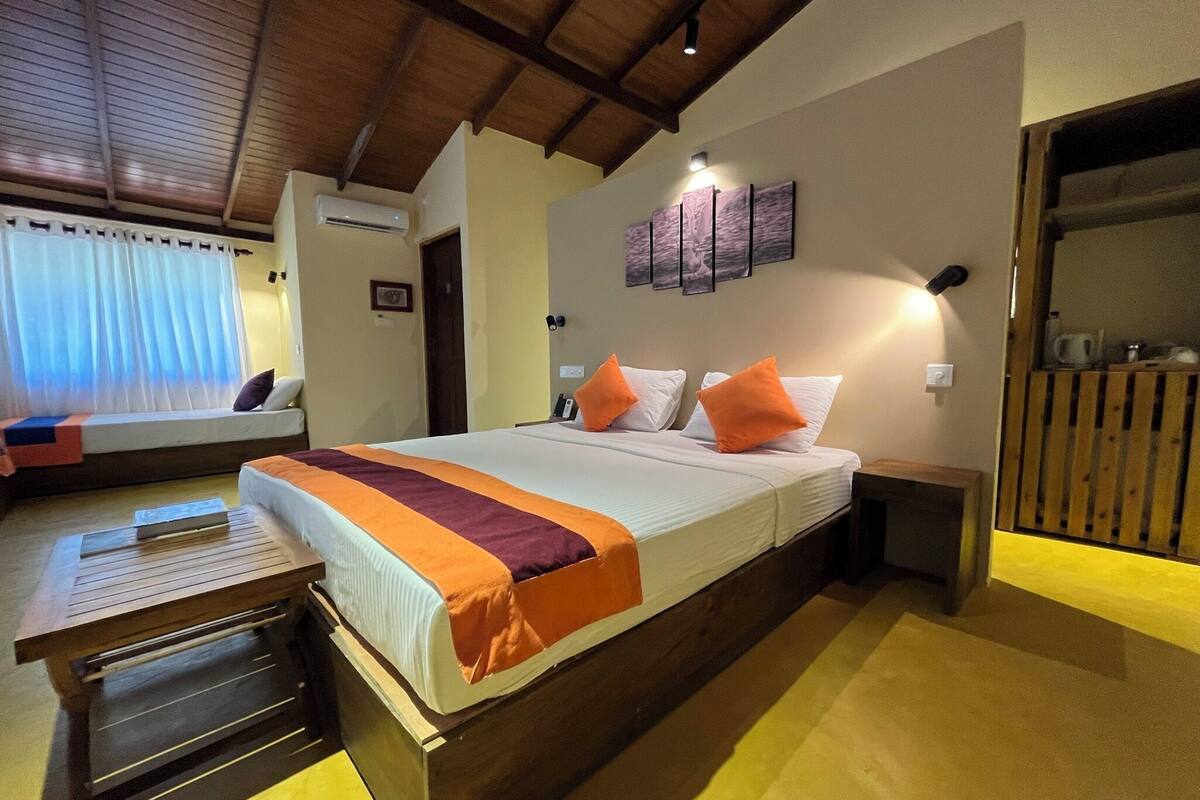A bedroom with a large bed, a bedside table, a wooden bench, and a wall-mounted air conditioner.