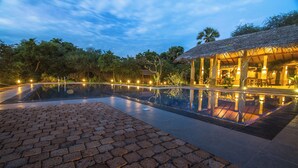 A swimming pool with a brick pathway leading to a building with a thatched roof. - Cloud Nine Lanka Resort Wilpattu (Wilpattu)