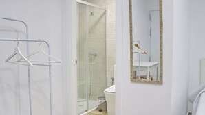 Un baño moderno con cabina de ducha de vidrio, lavamanos blanco y espejo con marco de madera.