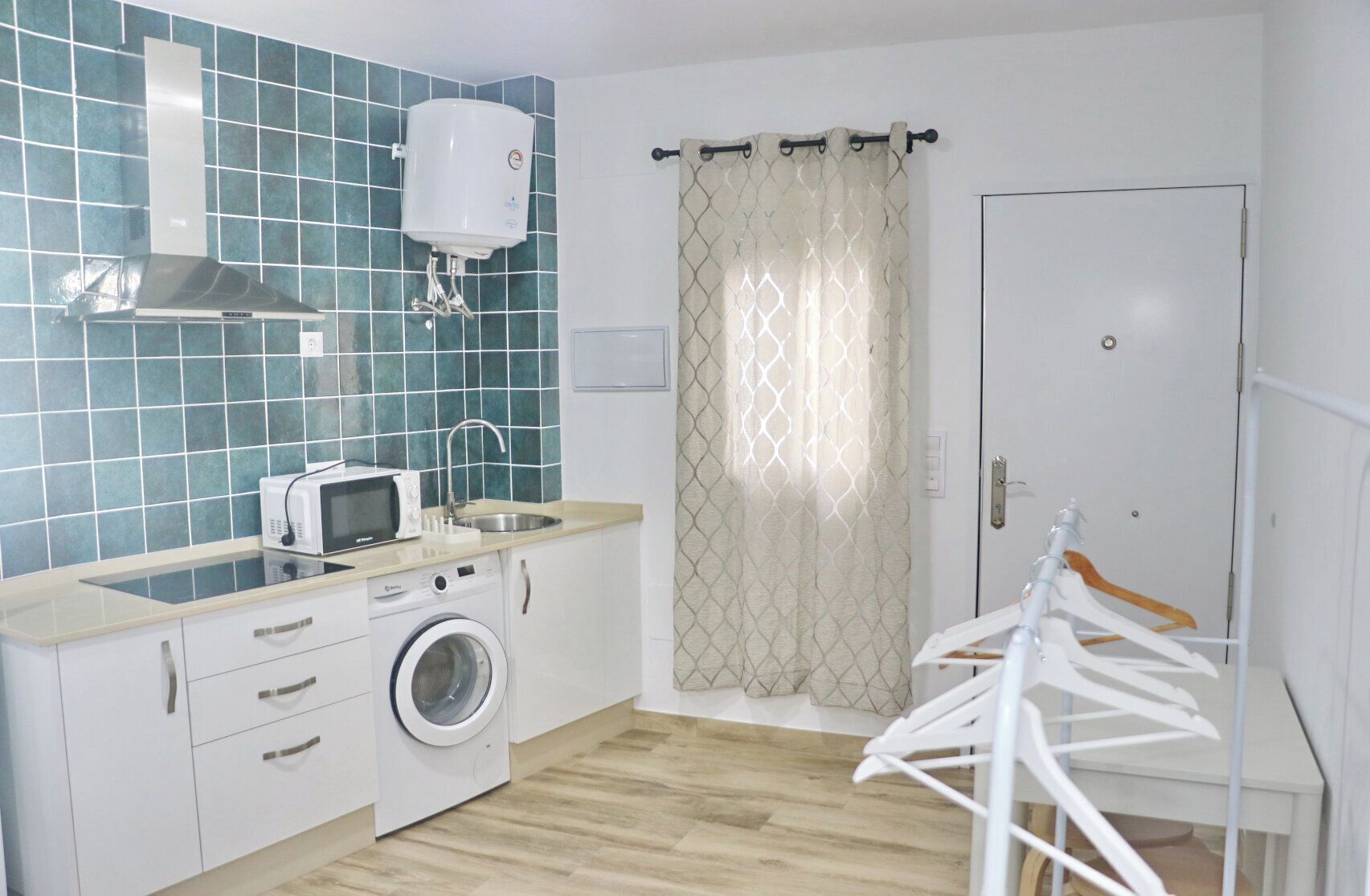 A compact kitchen with a microwave, washing machine, and a water heater.