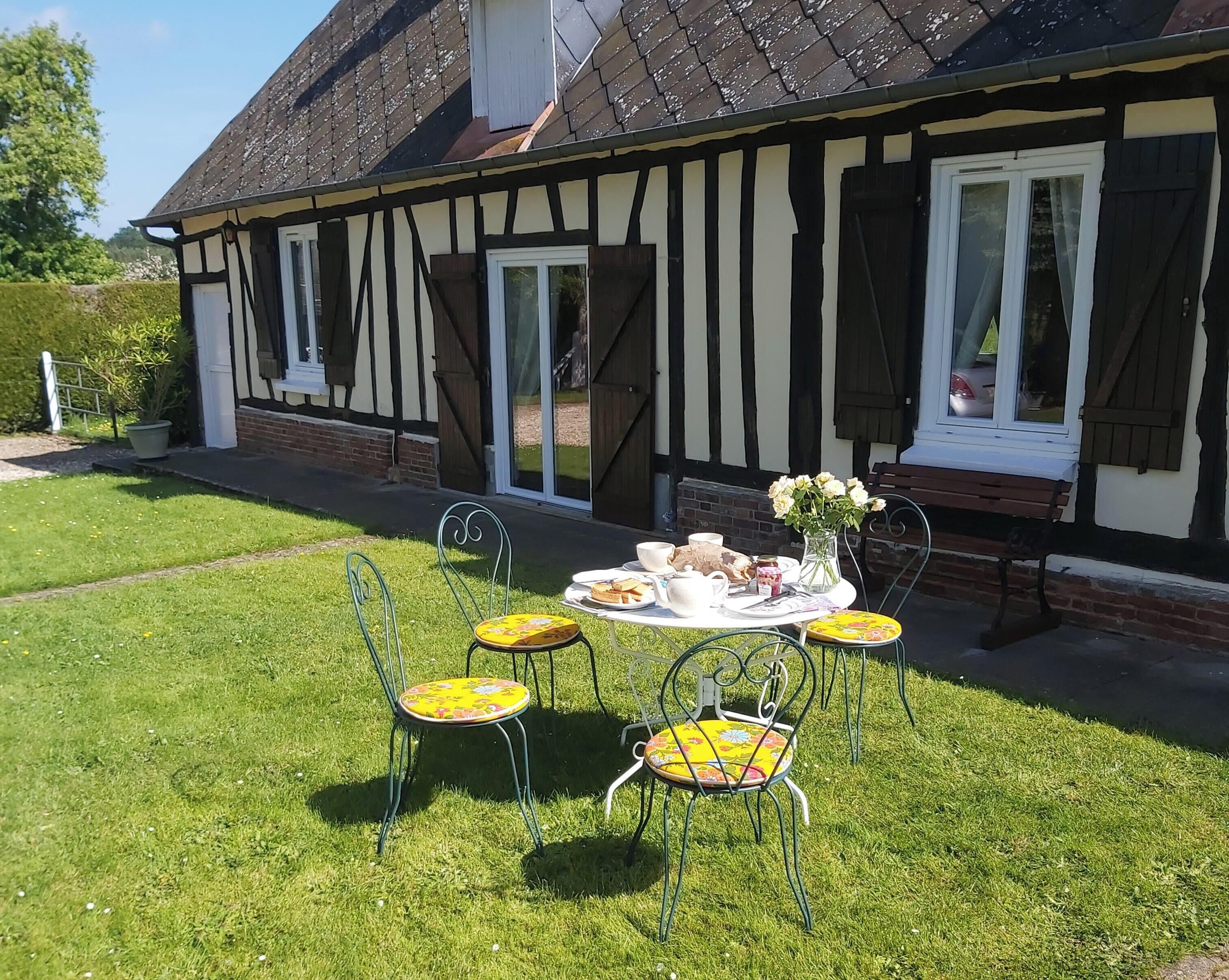 Une maison traditionnelle à colombages, avec une pelouse et une table préparée pour le thé.