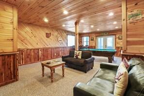A cozy cabin interior with a pool table, leather couches, and a billiards table. - Acacia Ridge Lodge | Hocking Hills, 4BR, Hot Tub (Rockbridge)