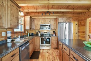 A kitchen with wooden cabinets, stainless steel appliances, granite countertops, and a wooden ceiling. - Acacia Ridge Lodge | Hocking Hills, 4BR, Hot Tub (Rockbridge)