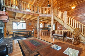 A spacious cabin interior with a wooden staircase, a dining area, and a kitchen. - Acacia Ridge Lodge | Hocking Hills, 4BR, Hot Tub (Rockbridge)