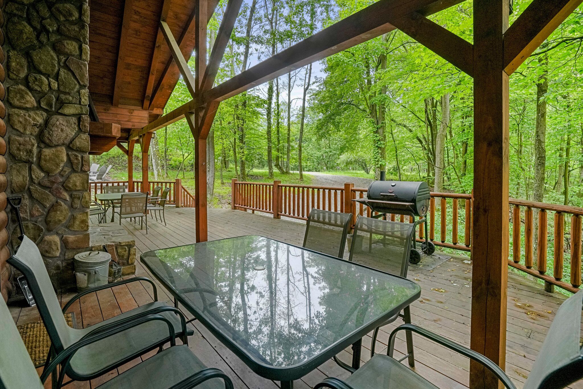 A covered deck with stone walls, outdoor furniture, and a grill.