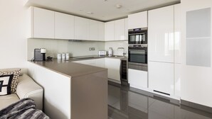 Een moderne keuken met witte kasten, een centraal kookeiland en inbouwapparatuur zoals een fornuis en oven.