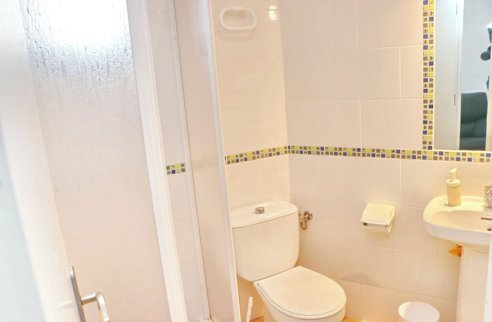 A bathroom with a toilet, sink, and shower area.