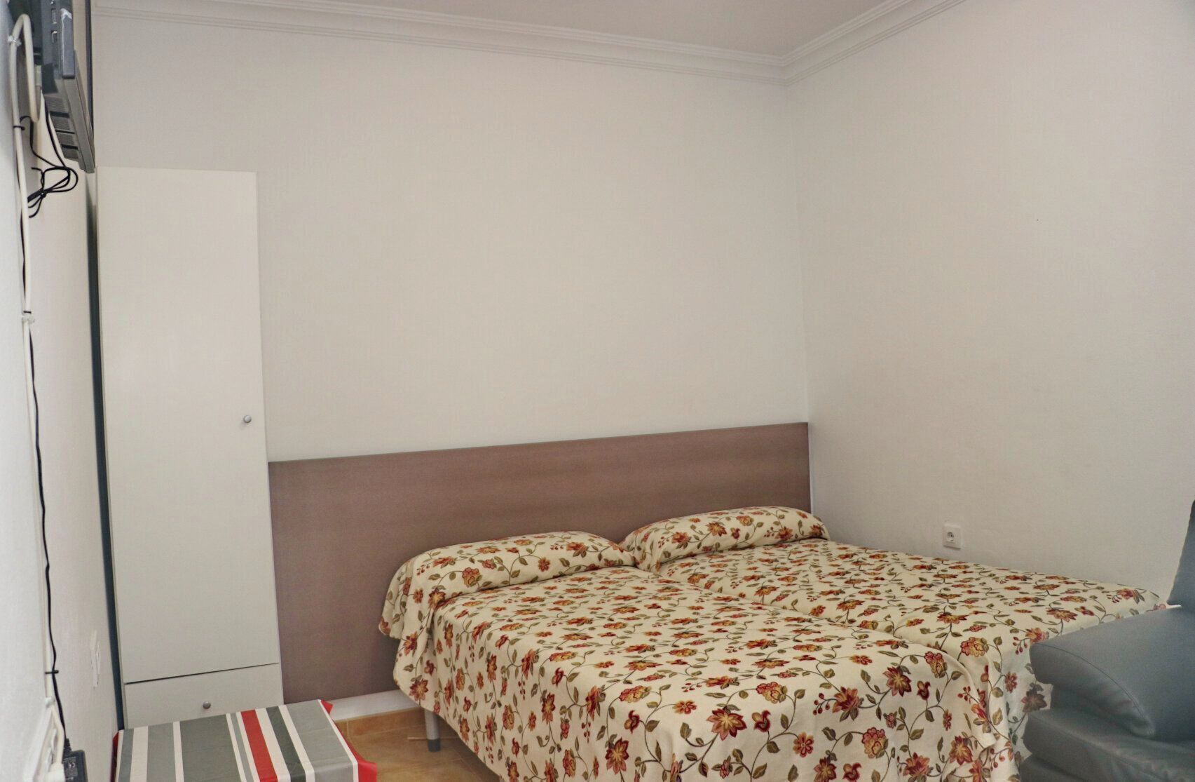 A bedroom with a bed, a chair, a wardrobe, and a small table.