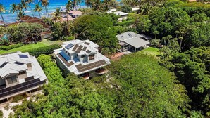 A coastal property with multiple houses, lush greenery, and a view of the ocean.
