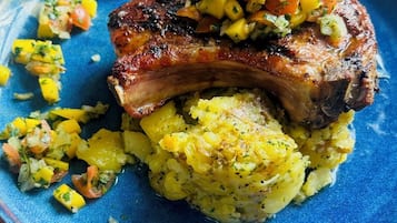 Une assiette composée de viande grillée, de purée de pommes de terre et d’une salsa à la mangue.