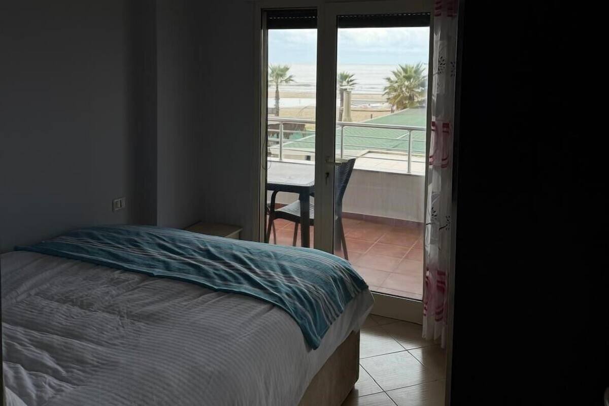 Un dormitorio con cama, lámpara en el techo y vistas a un balcón con mesa y sillas.