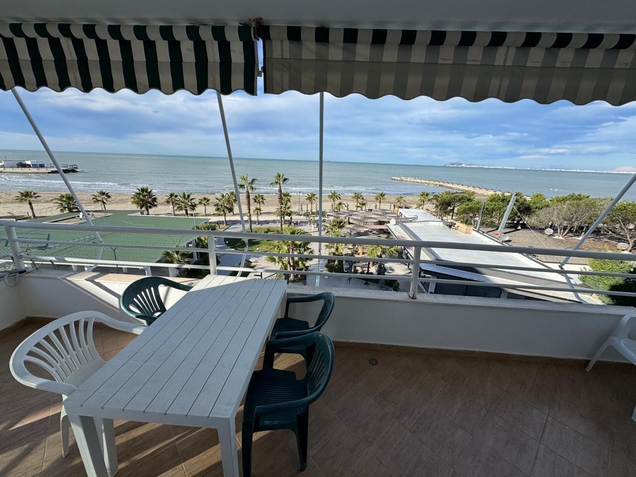 Un balcon avec vue sur la plage, une table et des chaises.