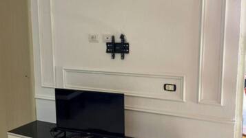 Une pièce équipée d’un meuble pour la télévision, d’un téléviseur à écran plat et d’une porte dotée d’une serrure.