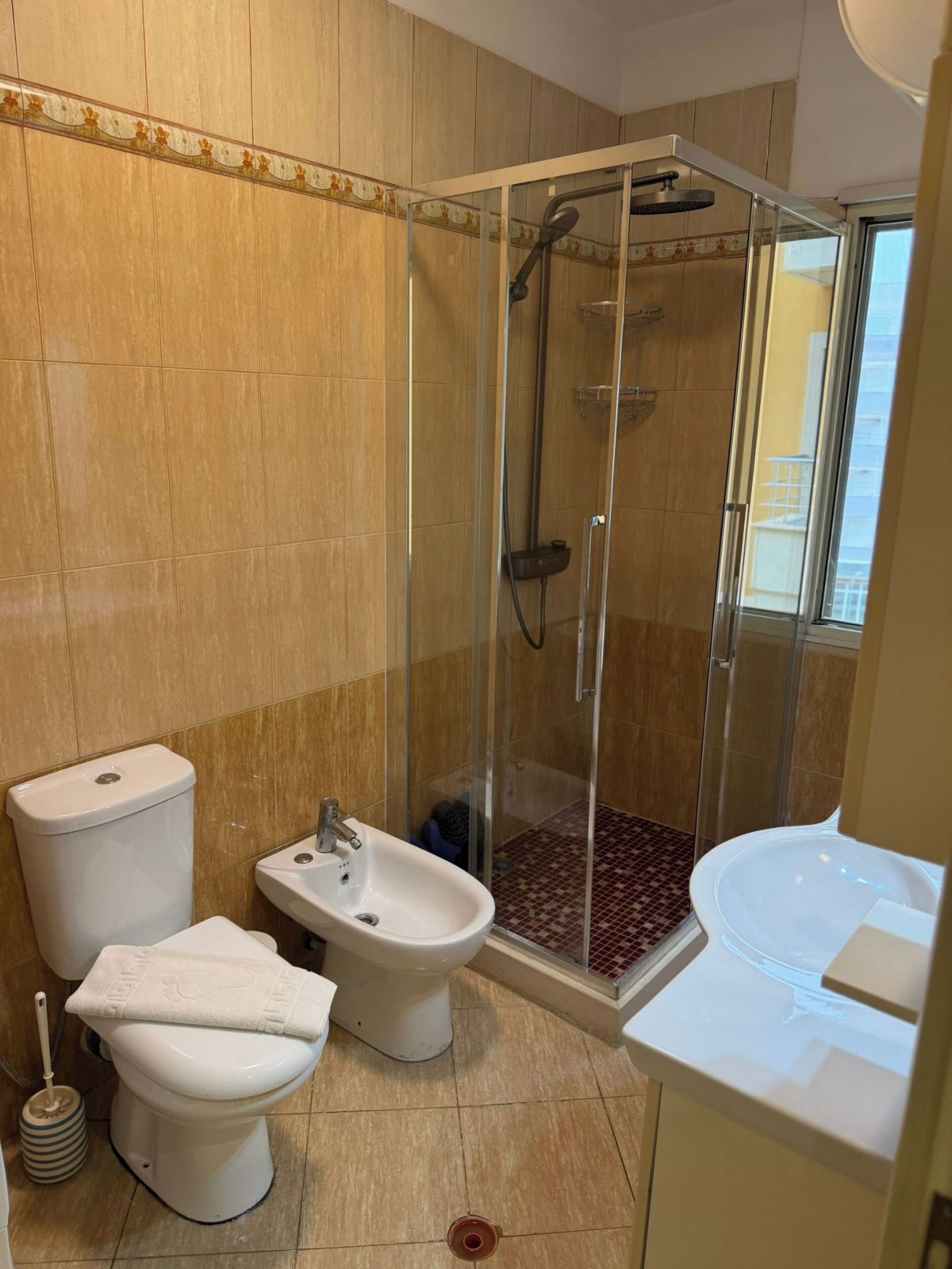 A bathroom with a glass-enclosed shower, a bidet, a toilet, and a bathtub.