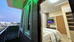 A modern bedroom with a bed, a TV, and a view of the outside. - Clarus Apartments (Ibadan)