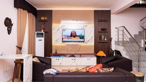 A modern living room with a marble TV stand, a sofa, and a staircase. - Clarus Apartments (Ibadan)