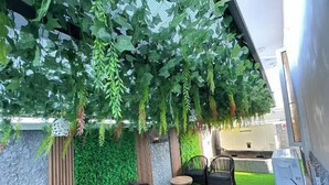 An outdoor seating area with artificial greenery, a stone wall, and a white structure. - Clarus Apartments (Ibadan)
