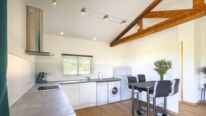 Une cuisine moderne avec des meubles blancs, un lave-vaisselle intégré et un coin repas comprenant une table et des chaises.