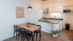 A compact kitchen with white cabinets, a wooden dining table, and black chairs.